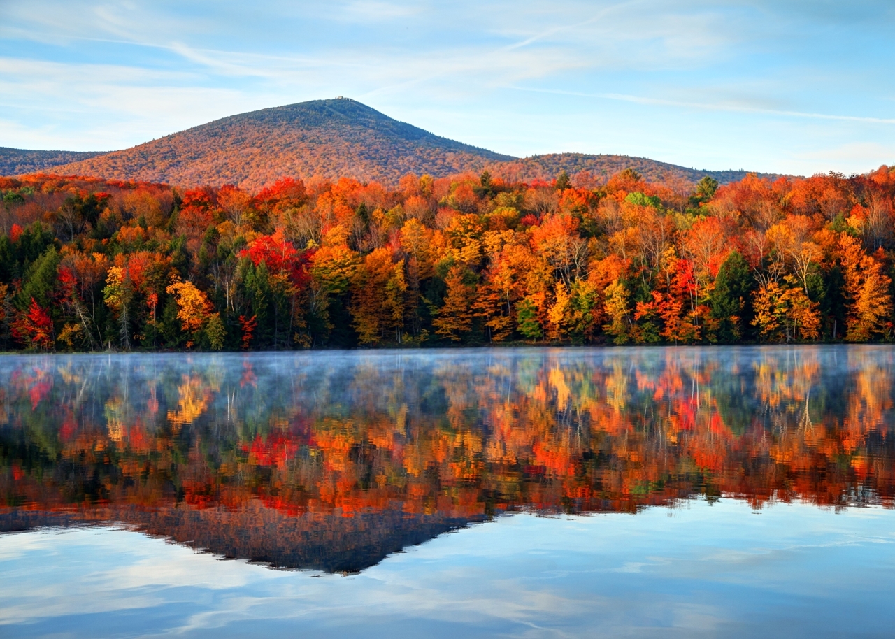 fall woods in Vermont with a lake reflecting the colorful leafs